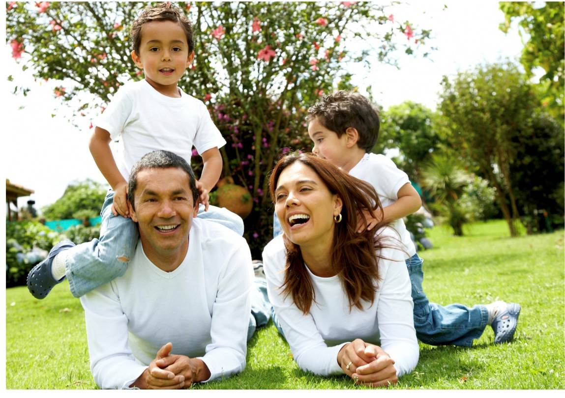 A family of four dressed in white shirts plays on the grass.
